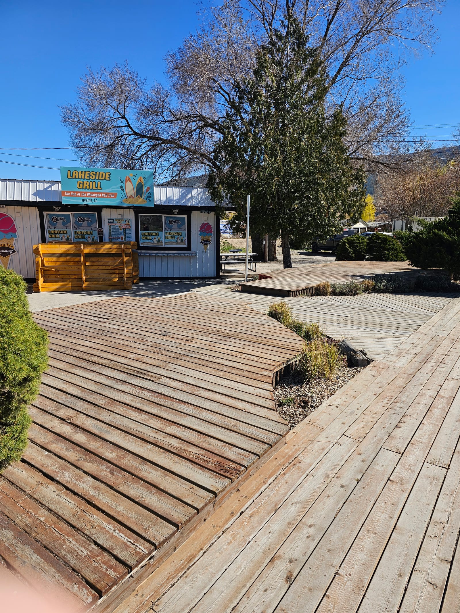 Lu Lou's Lakeside Grill viewed from the wood deck, with the order window, picnic tables and Wood Lake beach in Oyama, BC